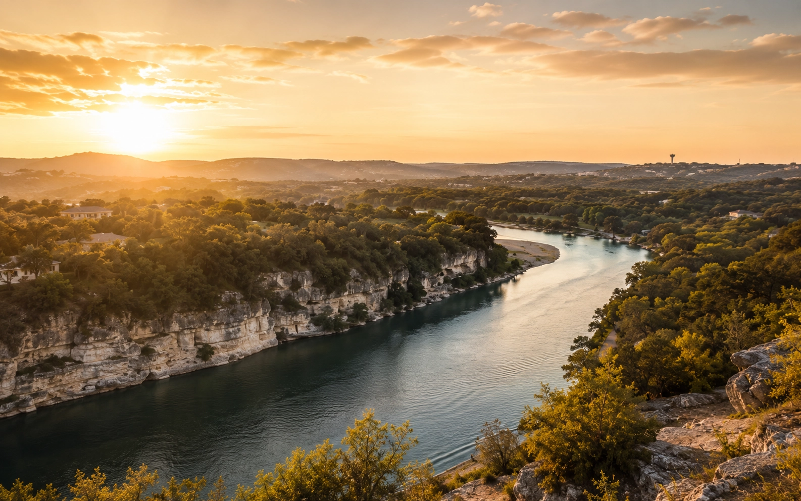 Wide editorial photograph of New Braunfels skyline at golden hour with river bend in foreground.