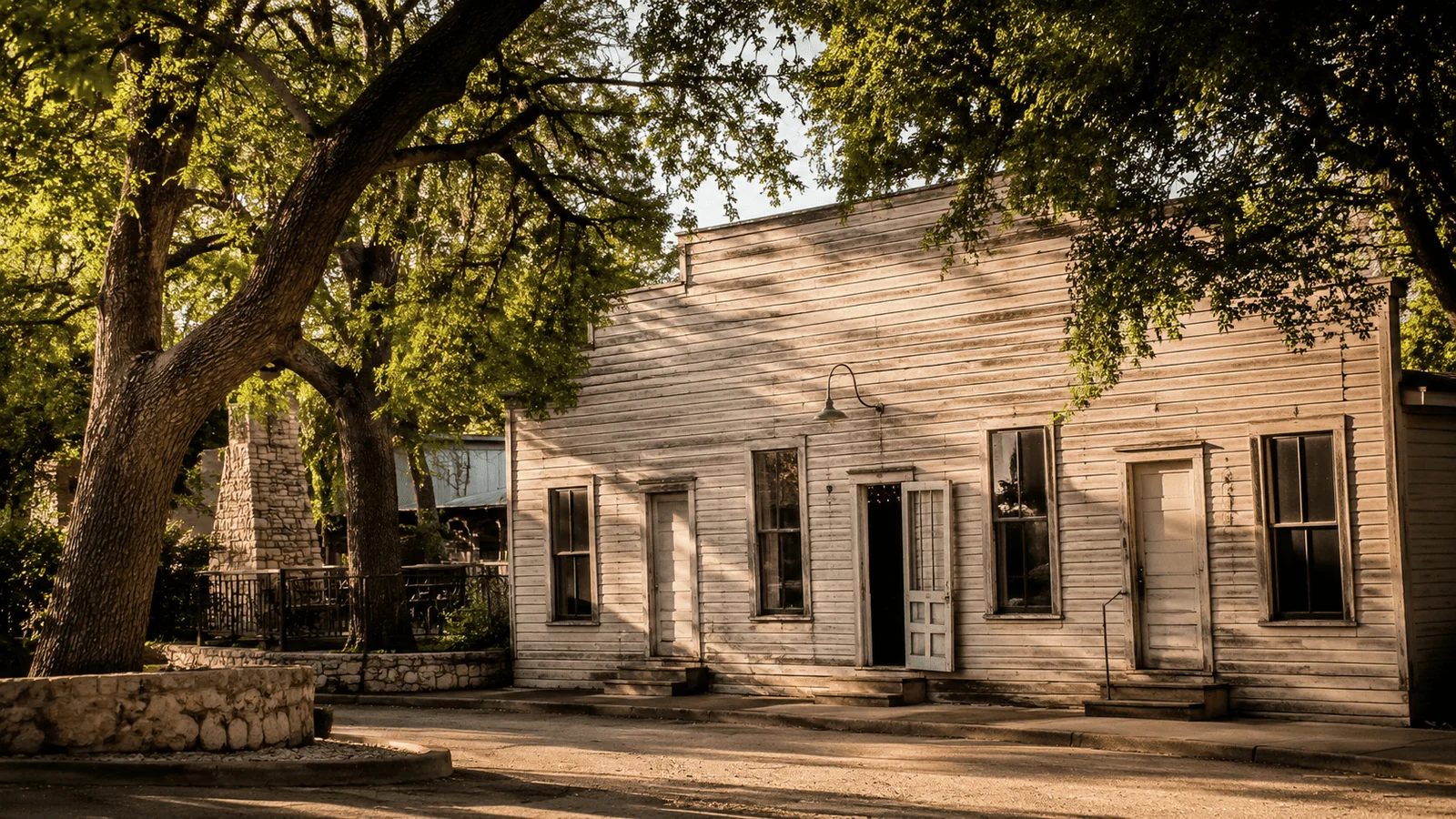 Gruene Hall's weathered wooden exterior surrounded by mature oak trees on a sunny afternoon in New Braunfels, Texas